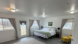 Ein Schlafzimmer mit einem Bett, Nachttischen, einer Lampe, einem Teppich und zwei mit Vorh ängen versehenen Fenstern.
