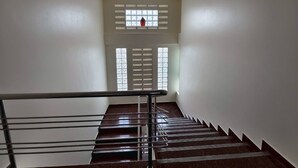 A staircase with a metal handrail, leading to a landing with a window with a red object on the sill. - 401 Budget Room Utilities Wifi Balcony in Ratchada (Bangkok)