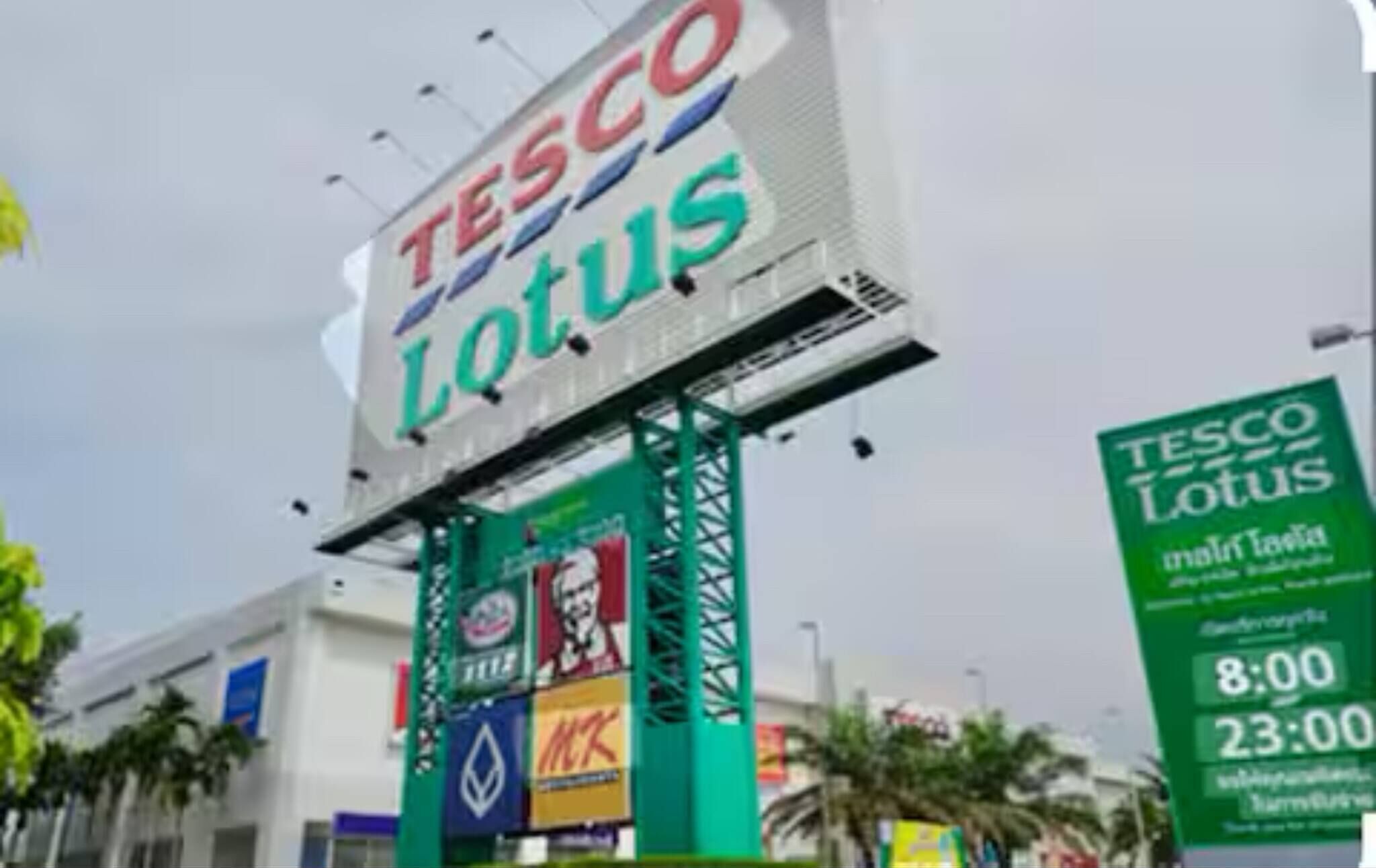 A large billboard with the Tesco Lotus logo and various brand advertisements.