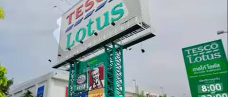 A large billboard with the Tesco Lotus logo and various brand advertisements.