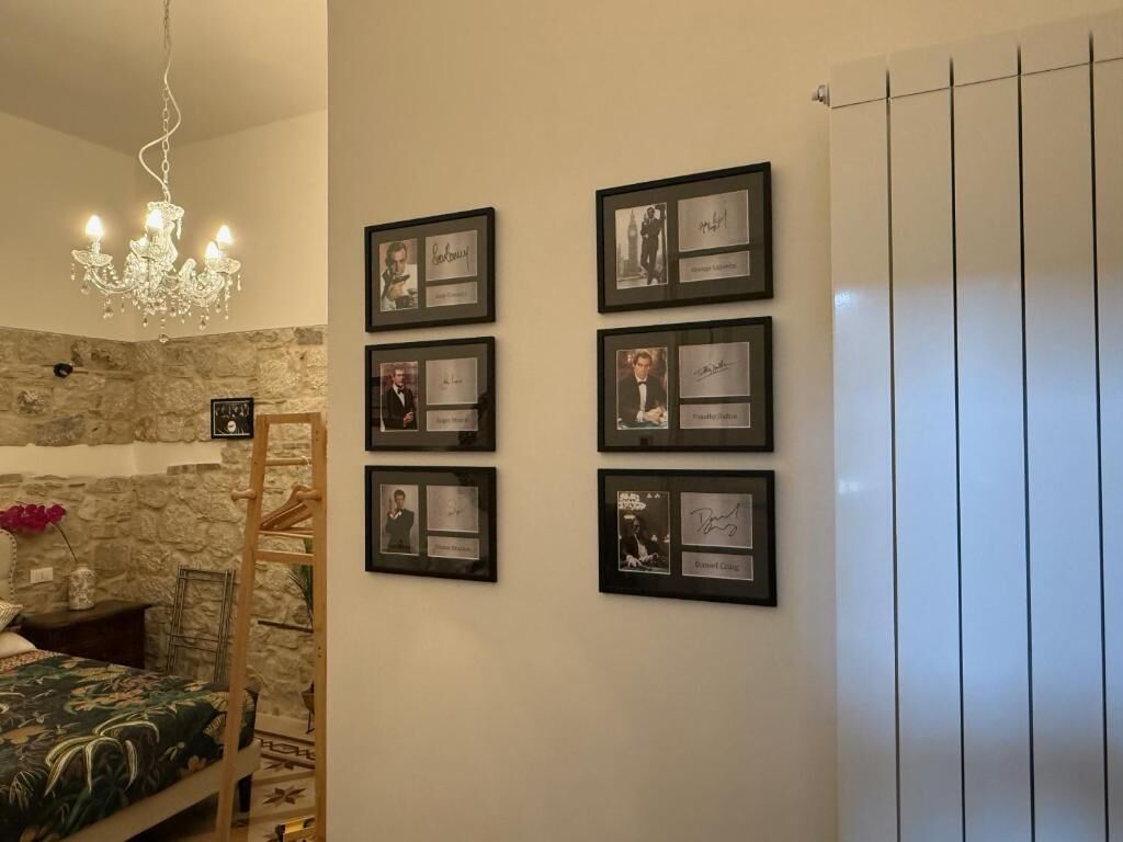Una camera da letto con parete in pietra, un letto con copriletto decorato, un lampadario e quadri appesi alla parete.