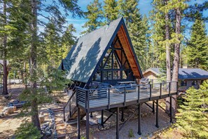 Eine Holzhütte mit einer Holzterrasse, einer Treppe und Blick auf den umliegenden Wald.