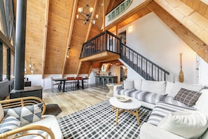 Ein Loft-Interieur mit Treppe, Holzbalken, einer Couch, einem Essbereich und einer Küche.