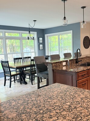 A kitchen with granite countertops, a dining area with wooden chairs, and large windows. - The Perfect Location in Saratoga Springs (Saratoga Springs)