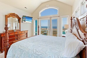A bedroom with a large bed, a dresser, a mirror, and a television. - 6 Bdrm, Ocean and Sound Views, Game Room, Theater, DOGS OK, Elevator, Pool, Kiddie Pool, Hot Tub (Hatteras)