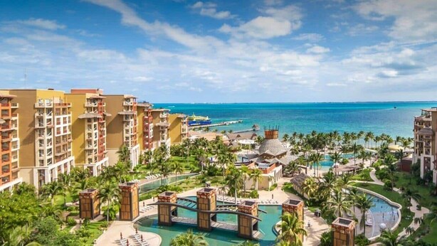 A resort with multiple buildings, a central pool area, and a view of the ocean. - CHRISTMAS WEEK / Cancun 3BR Oceanfront Resort (Cancún)