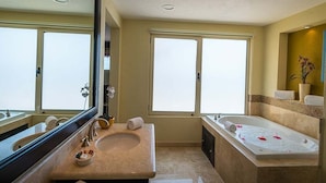 A bathroom with a large mirror, a bathtub, a sink, and a window. - CHRISTMAS WEEK / Cancun 3BR Oceanfront Resort (Cancún)