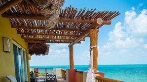 A balcony with a hammock, chairs, and a view of the ocean. - CHRISTMAS WEEK / Cancun 3BR Oceanfront Resort (Cancún)