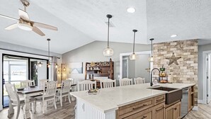 Un'ampia cucina con una grande isola, mobili in legno e luci a sospensione.