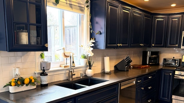 Una cucina moderna con mobili scuri, elettrodomestici in acciaio inossidabile e una grande isola.