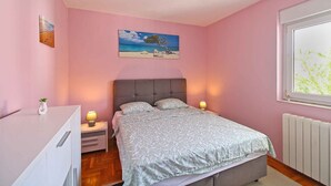Ein Schlafzimmer mit einem Bett, Nachttischen, einem Fenster und einem Bild an der Wand.