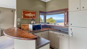 Una cocina con una encimera curva, microondas, armarios y una ventana con vistas.