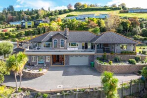A two-story house with a large driveway, a garage, and a landscaped front yard.