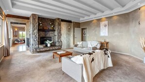 Un amplio salón con chimenea de piedra, un sofá y una mesita de centro.