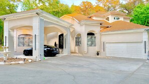 Une maison avec un garage, une allée et une fontaine.
