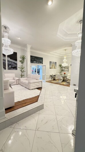 A spacious living room with a white sectional sofa, a wooden platform, and a dining area with a chandelier. - This beautiful Luxury Mini Mansion,  4 bedroom 4 bath estate in Atlanta GA. (Atlanta)