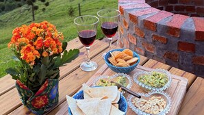A table with food and drinks, a brick oven, and a scenic view of hills. - Country house in the mountains of Santa Catarina, at 1000m altitude, surrounded by nature. (Alfredo Wagner)