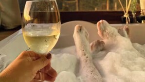 A person holding a glass of white wine, a bathtub with bubbles, and a view of trees through a window. - Country house in the mountains of Santa Catarina, at 1000m altitude, surrounded by nature. (Alfredo Wagner)