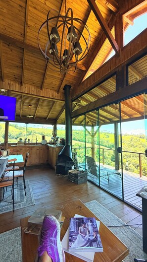 A wooden interior with a large fireplace, a dining area, and a view of the countryside. - Country house in the mountains of Santa Catarina, at 1000m altitude, surrounded by nature. (Alfredo Wagner)