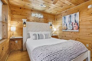 Ein Zimmer mit Holzwänden, einem Bett, einem Neonlicht und einem Gemälde von Gitarren.