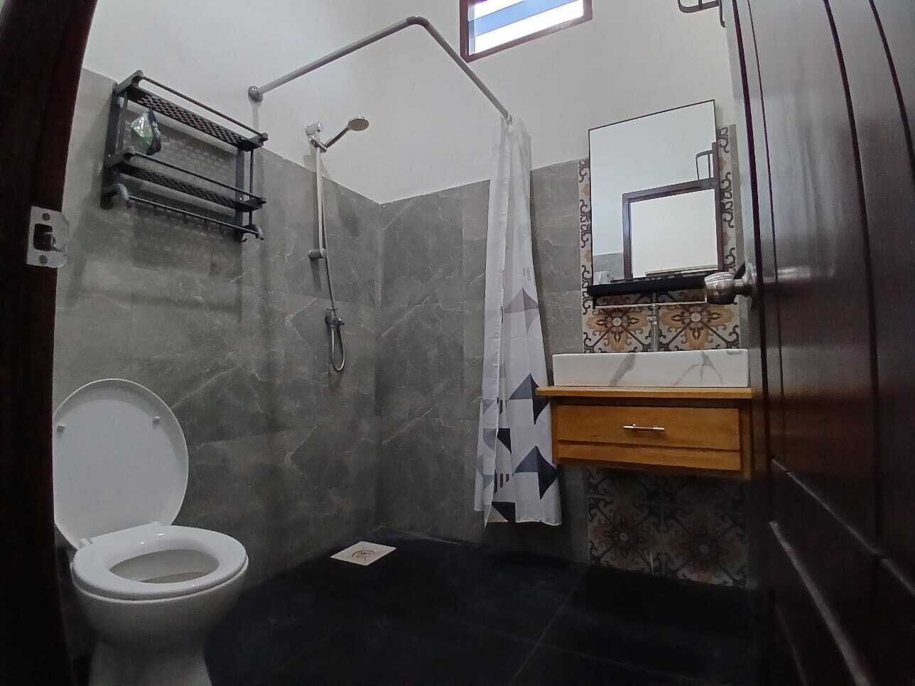 A bathroom with a toilet, shower, and a mirror above the sink.
