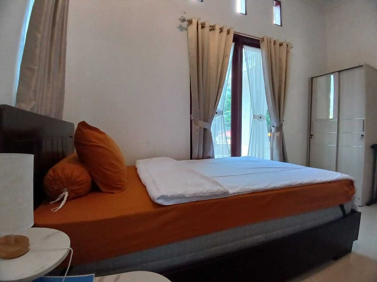 A bedroom with a bed, pillows, a bedside table, and a wardrobe.