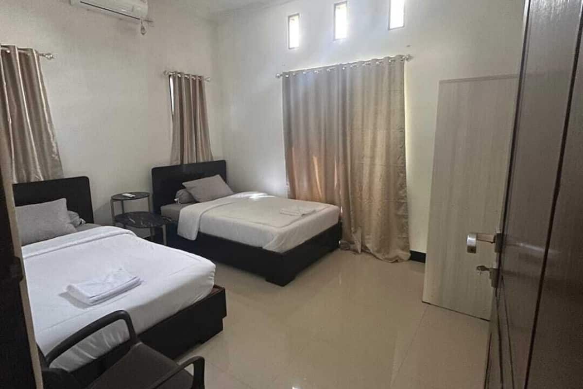 Een hotelkamer met twee bedden, een bureau, een stoel, een airconditioning en een deur.
