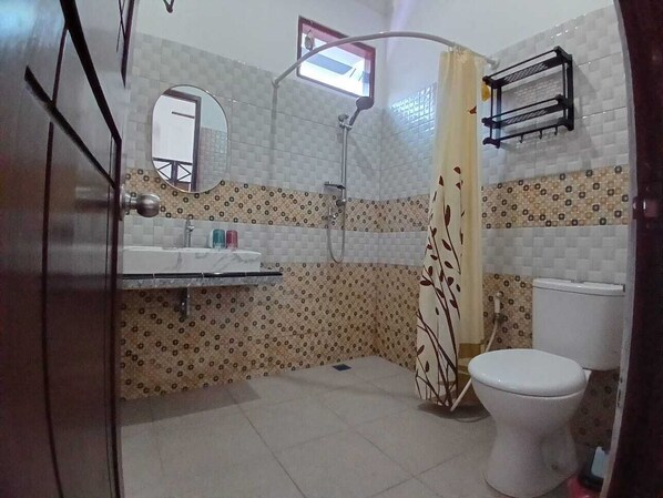 Un baño con inodoro, lavabo, ducha y ventana.