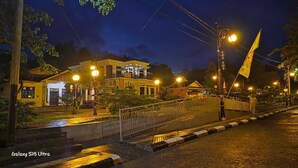 A nighttime street scene with a building, streetlights, and a flag. - D' Kabong SIRIH Homestay (Bandanaira)