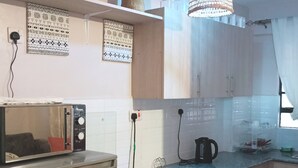 Eine Küche mit Kühlschrank, Mikrowelle, Herd und einer Pendelleuchte.