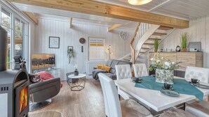 A modern living room with a fireplace, a dining area, and a staircase. - Cozy home in Wandlitz with WiFi (Wandlitz)