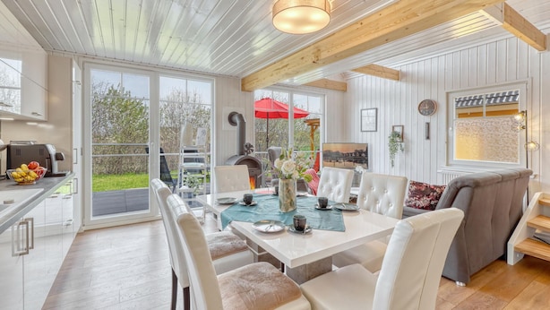A spacious dining area with a table set for four, surrounded by white chairs, and a cozy seating area with a sofa and armchairs. - Cozy home in Wandlitz with WiFi (Wandlitz)