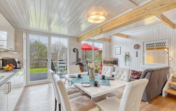 A spacious dining area with a table set for four, surrounded by white chairs, and a cozy seating area with a sofa and armchairs. - 3 bedroom awesome home in Wandlitz (Wandlitz)