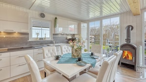 A modern kitchen with white cabinetry, a dining area with a table set for two, and a wood-burning stove. - Cozy home in Wandlitz with WiFi (Wandlitz)