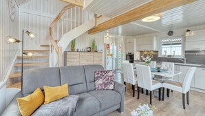A modern interior with a grey sofa, wooden staircase, and a dining area with white chairs. - Cozy home in Wandlitz with WiFi (Wandlitz)