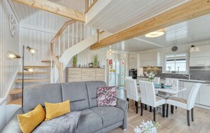 A modern interior with a grey sofa, wooden staircase, and a dining area with white chairs. - 3 bedroom awesome home in Wandlitz (Wandlitz)