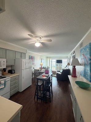 A kitchen with a dining area, wooden flooring, and a ceiling fan.