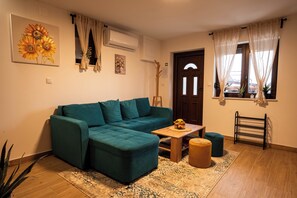 A living room with a teal sofa, a wooden coffee table, a patterned rug, and a door with curtains.