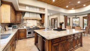 A spacious kitchen with a large island, wooden cabinets, and a modern stove. - Luxury Estate with Pool, Desert Views & Casita (Cave Creek)