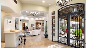A spacious living area with a central seating area, a kitchen, and a large open door leading to an outdoor patio. - Luxury Estate with Pool, Desert Views & Casita (Cave Creek)