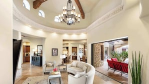 A spacious living area with a chandelier, a sofa, a coffee table, and a dining area with chairs. - Luxury Estate with Pool, Desert Views & Casita (Cave Creek)
