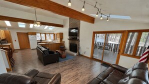 A spacious living area with a fireplace, leather sofas, a kitchen, and a deck with a view. - Hike, Bike & Ski, 12 Mi to Slopes: Serene Cabin-Greer, AZ (Greer)