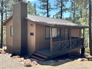 A rustic cabin with a wooden exterior, a chimney, a porch with a railing, and a number '2' sign. - Cozy Cabin in Greer: Hike, Bike & Ski! (Greer)