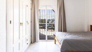 Een slaapkamer met een bed, een kledingkast en uitzicht door een raam.