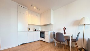 Een moderne keuken met witte kasten, een ingebouwde oven en een eethoek met twee stoelen en een tafel.
