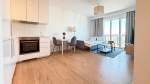 Een moderne hotelkamer met kitchenette, een eethoek, een bed en een balkon met uitzicht.