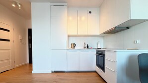 Een moderne keuken met witte kasten, een inbouwoven en een houten vloer.
