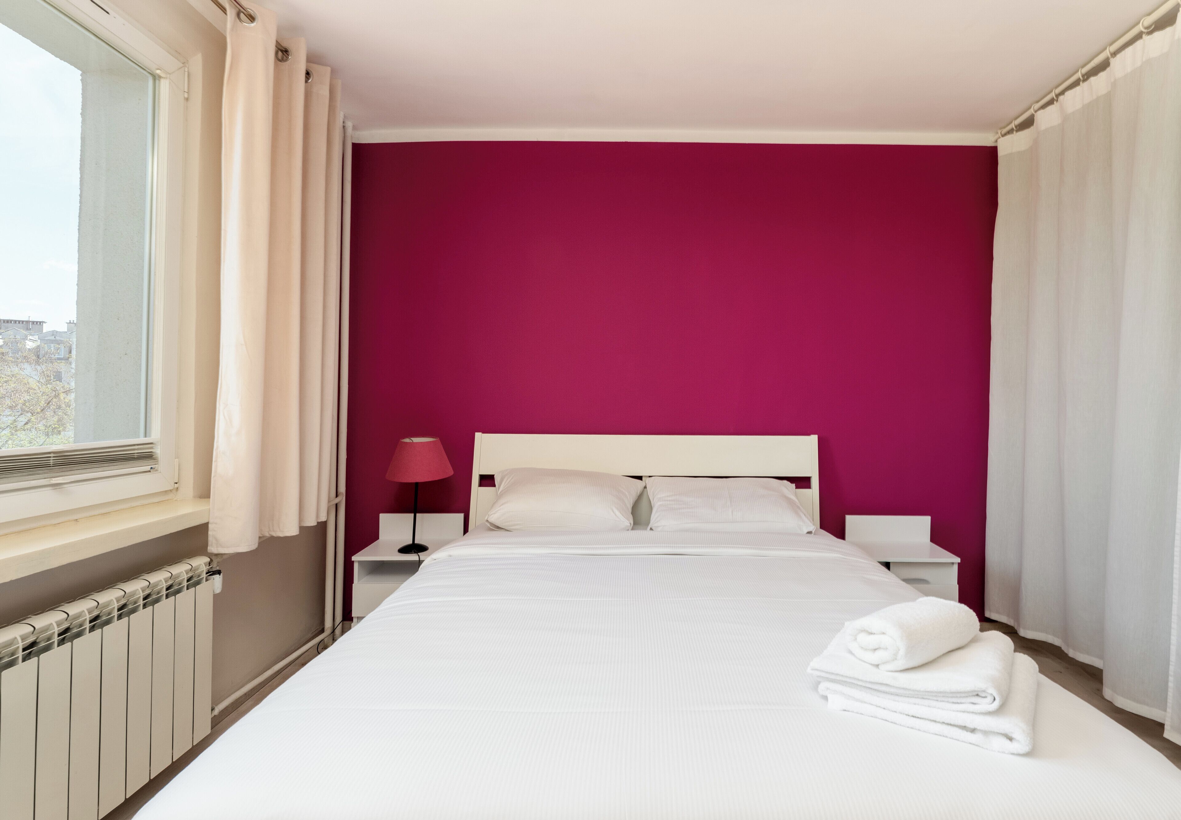 Une chambre d’hôtel avec un lit, une table de chevet, une lampe, une fenêtre et une vue sur la ville.