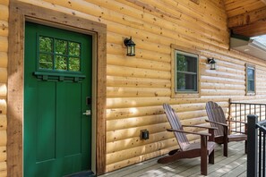 A wooden cabin with a green door, two windows, and a porch with two Adirondack chairs. - All New True Log Cabin Near Thunder Ridge&Big Cedar_Pvt Hot Tub_Bonus Loft_Free Daily Tickets (Ridgedale)