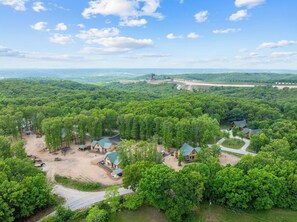 A forested area with several cabins and a large building, likely a lodge or resort, surrounded by dense trees and a clear sky. - All New True Log Cabin Near Thunder Ridge&Big Cedar_Pvt Hot Tub_Bonus Loft_Free Daily Tickets (Ridgedale)